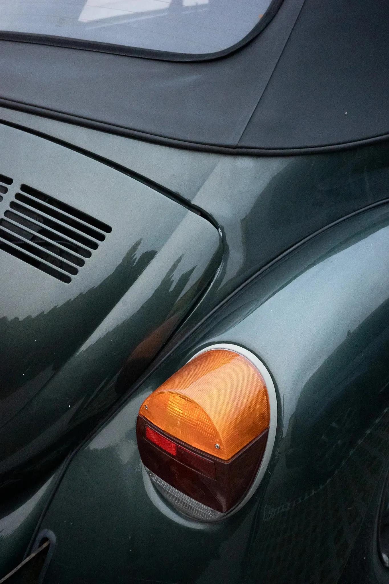 The rear light of an old green car.